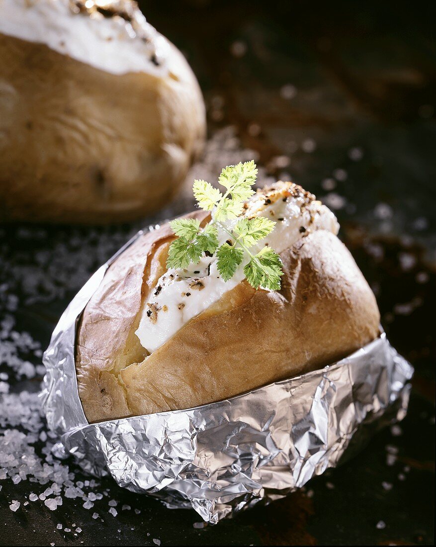 Baked potato with sour cream dip in opened foil