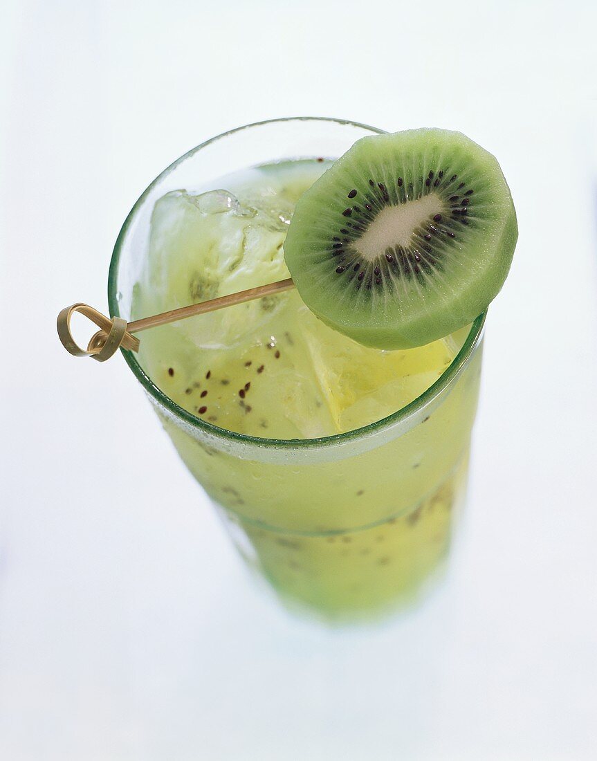 A glass of kiwi juice with ice cubes, garnished with kiwi slice