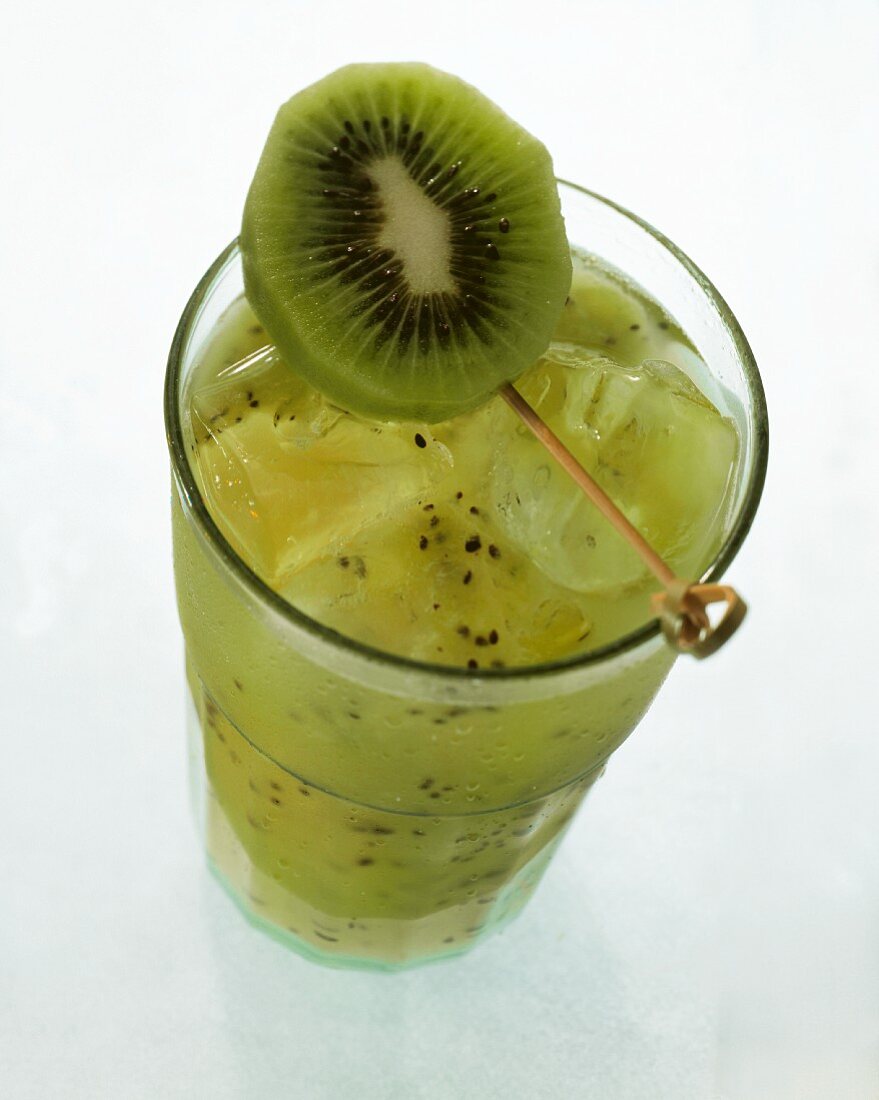 Kiwi juice with ice cubes in glass with kiwi slice garnish