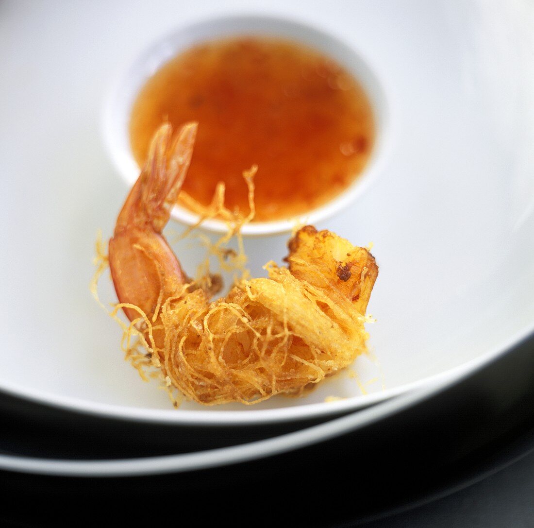 Eine fritierte Garnele im Reisnudelmantel mit Asia-Dip
