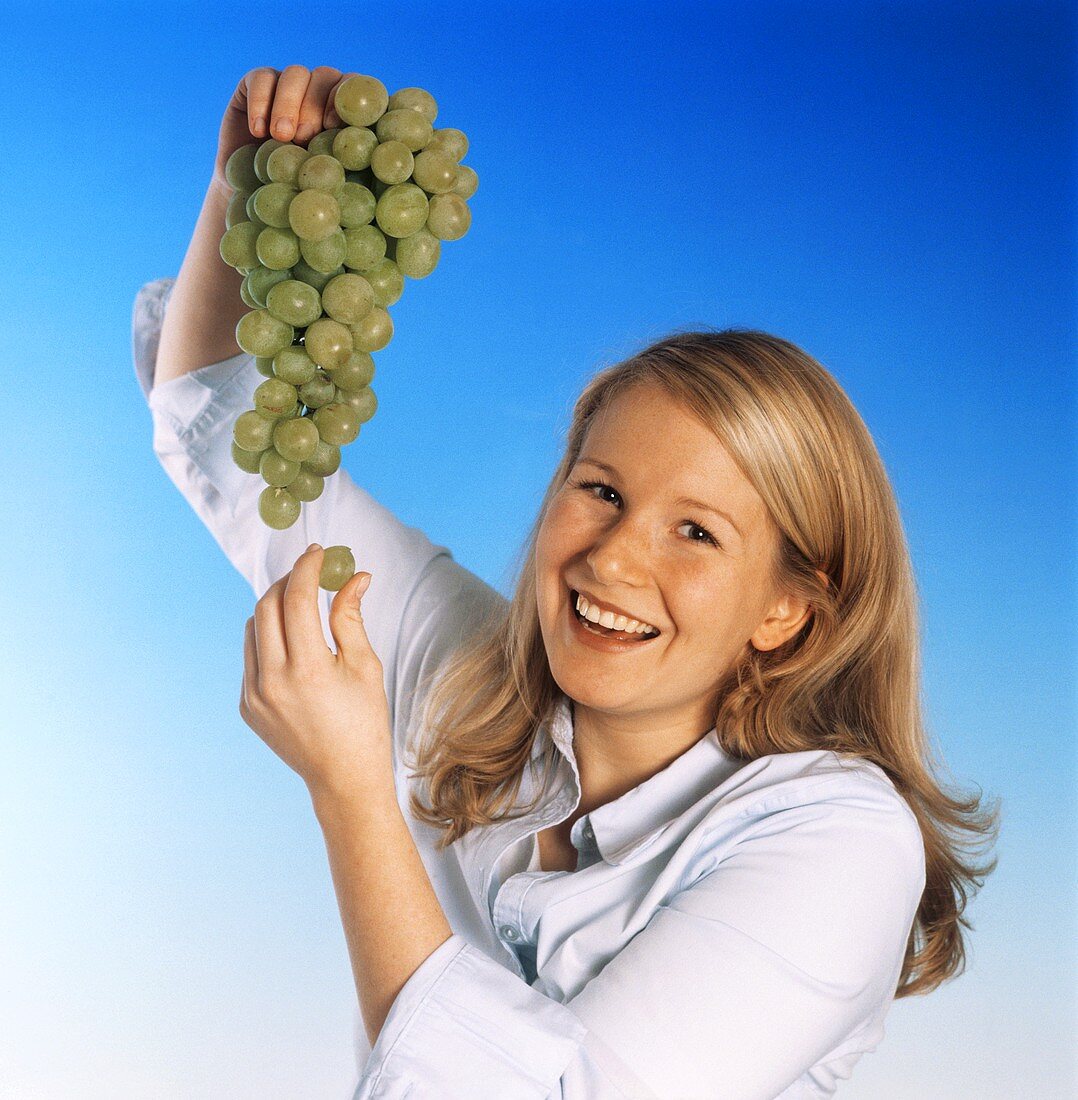 Young blond woman holding green grapes