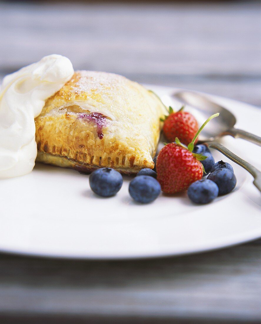 Turnover with berry filling and fresh berries on plate