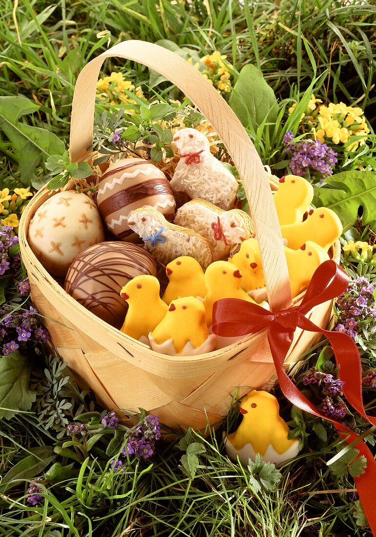 Chip basket in meadow with Easter baking, chocolate Easter eggs