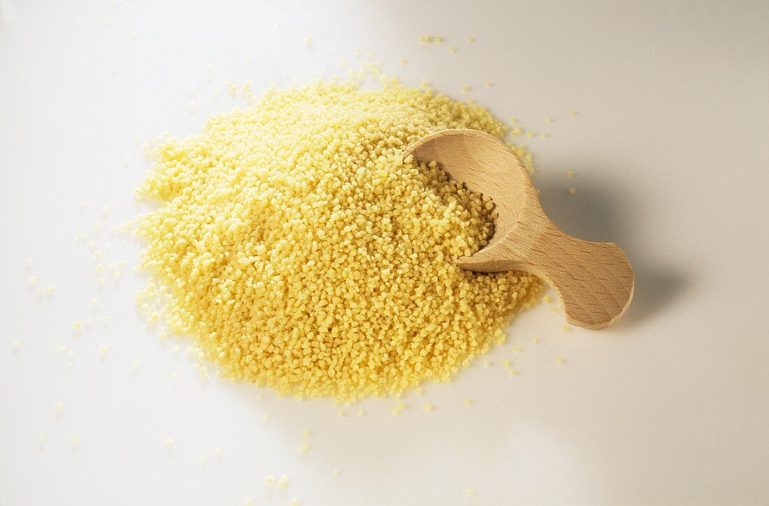 A pile of couscous with a wooden spoon in it