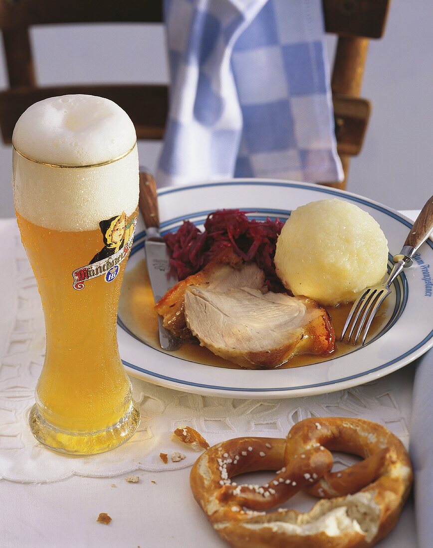 Schweinebraten mit Rotkohl & Knödel; daneben Weissbier, Breze