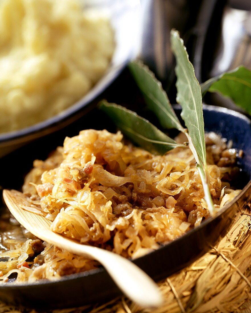 Pan-cooked sauerkraut with bacon, mashed potato behind