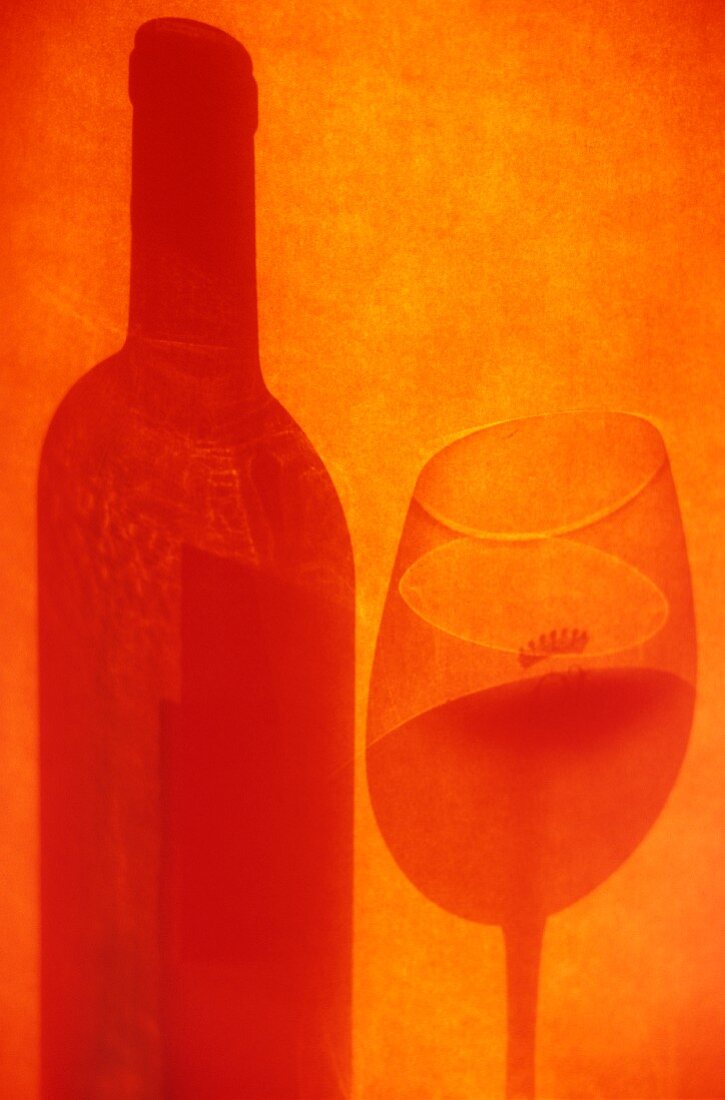 Schatten von Rotweinglas und -flasche auf oranger Fläche