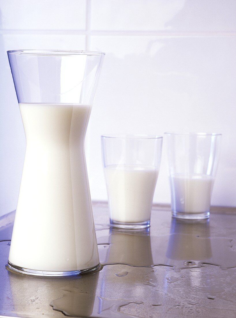 Milch in zwei Gläsern und Glaskrug