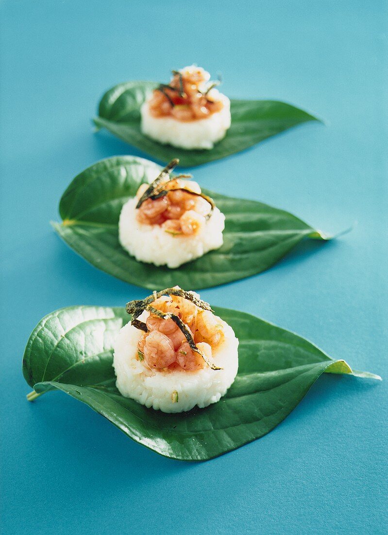Sushi style snacks with rice and shrimps on leaves 