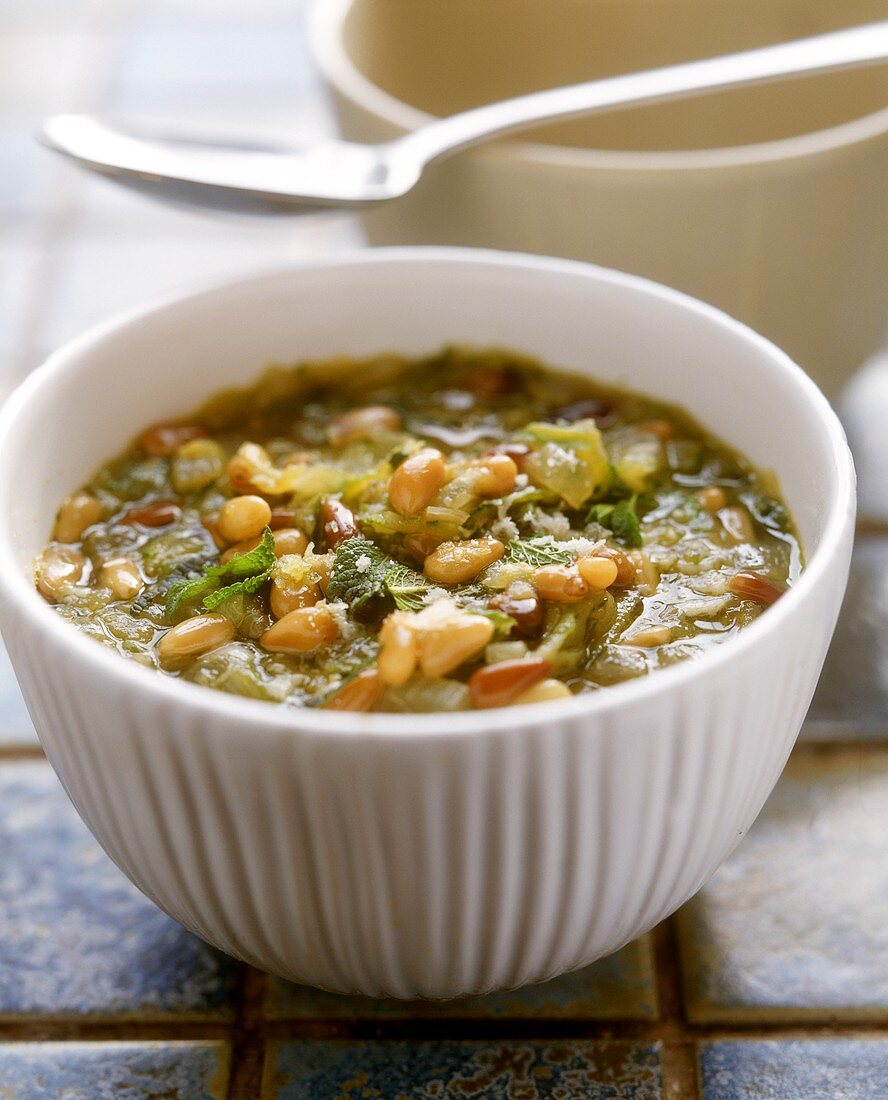 Vegetable soup with mint and peanuts in white bowl