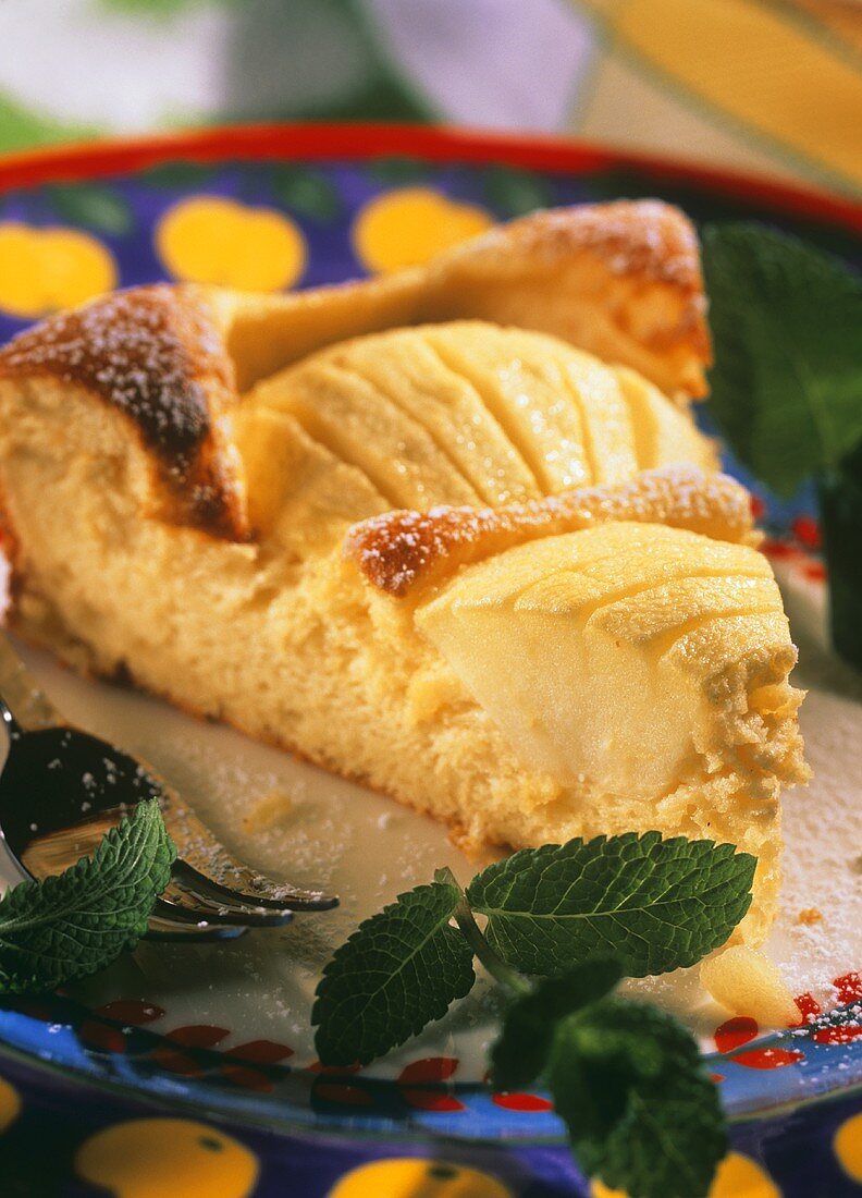 Ein Stück Apfel-Blitzkuchen auf Teller, daneben Minzblättchen