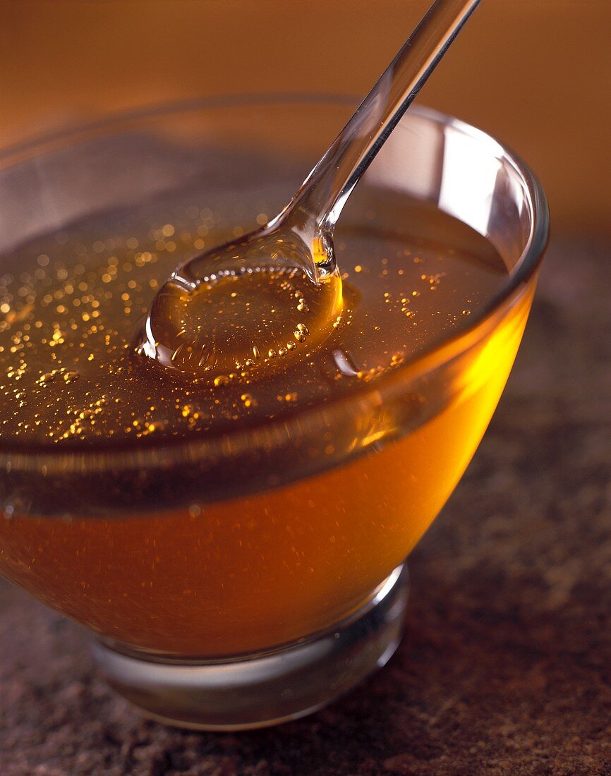 Honey with a glass spoon in glass bowl