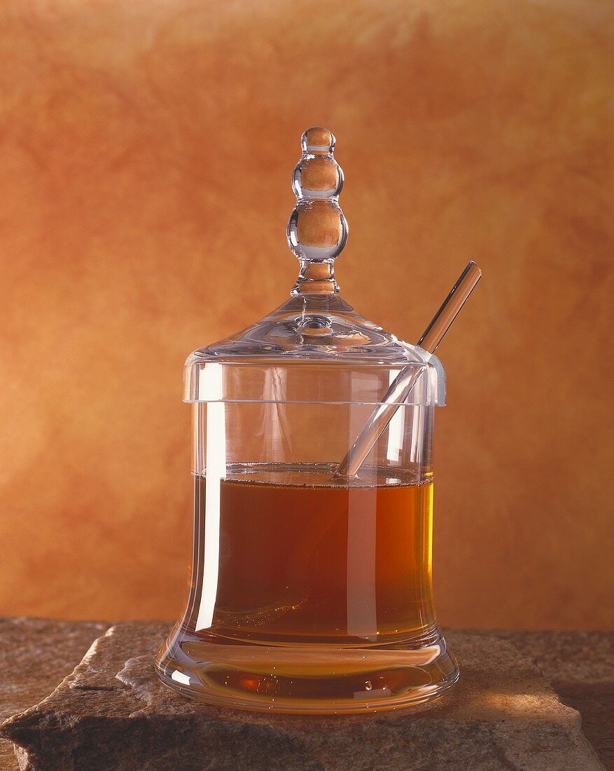 Honey with glass spoon in decorative jar