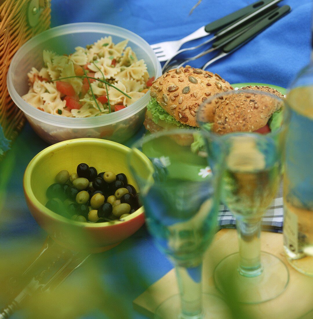 Picnic with pasta salad, olives, rolls and wine