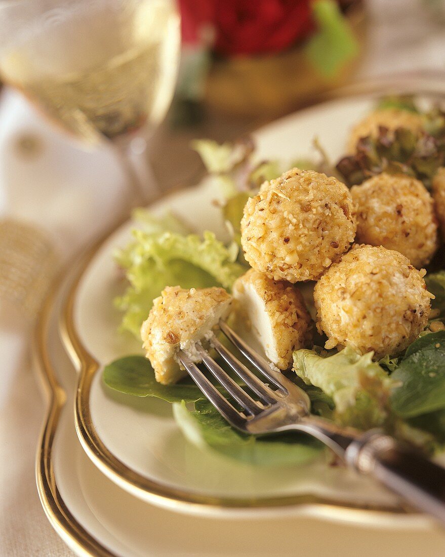Goat's cheese balls with nut crust on salad leaves