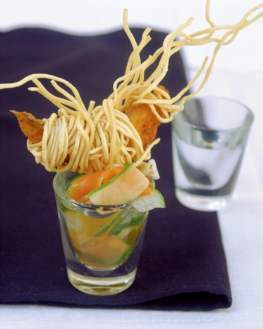 Fried shrimps with udon noodles and vegetables in a glass 