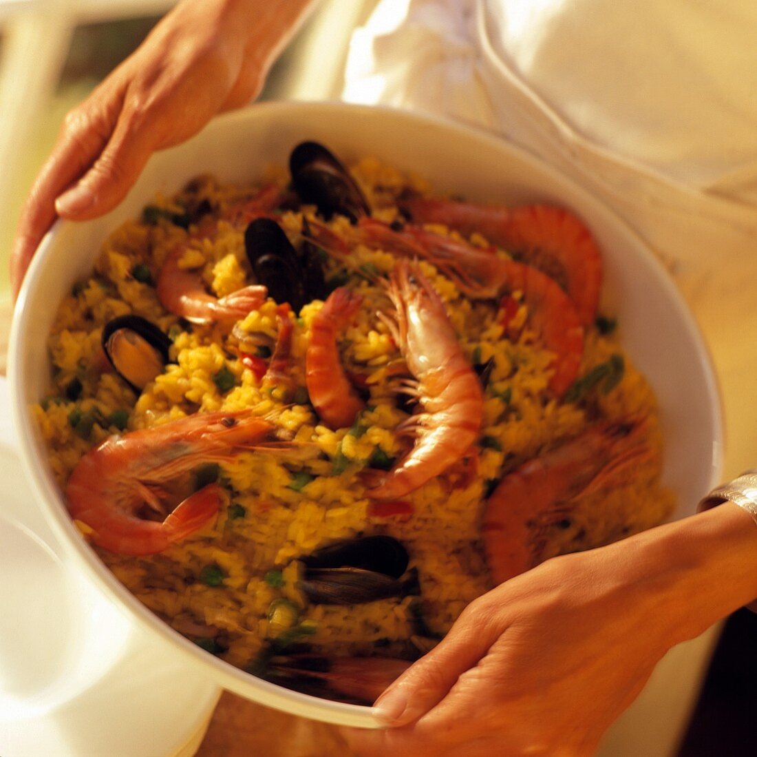 Hands holding a dish of paella