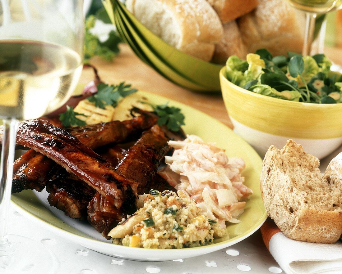Spare ribs on plate with salads and white bread