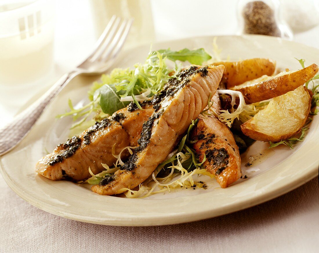 Salmon fillet with pesto and baked potatoes on salad