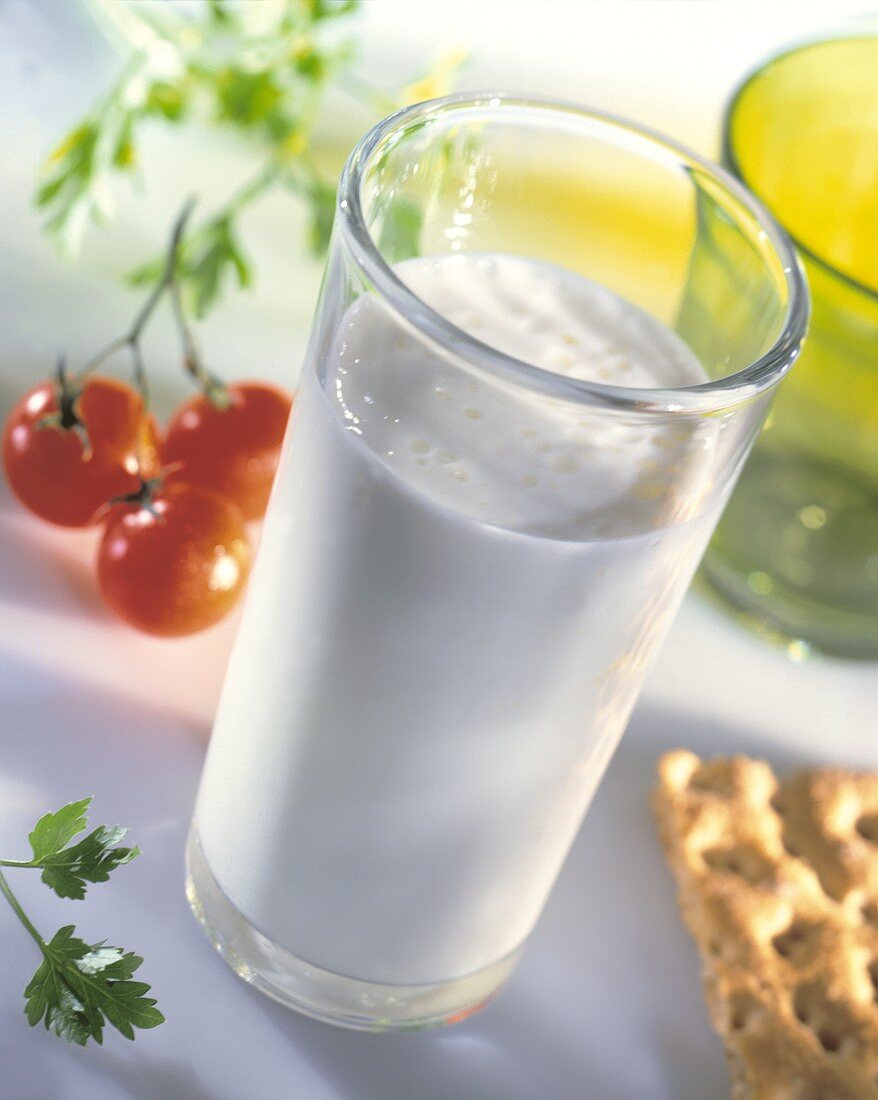 Glas mit Milch, im Hintergrund Knäckebrot & Tomaten