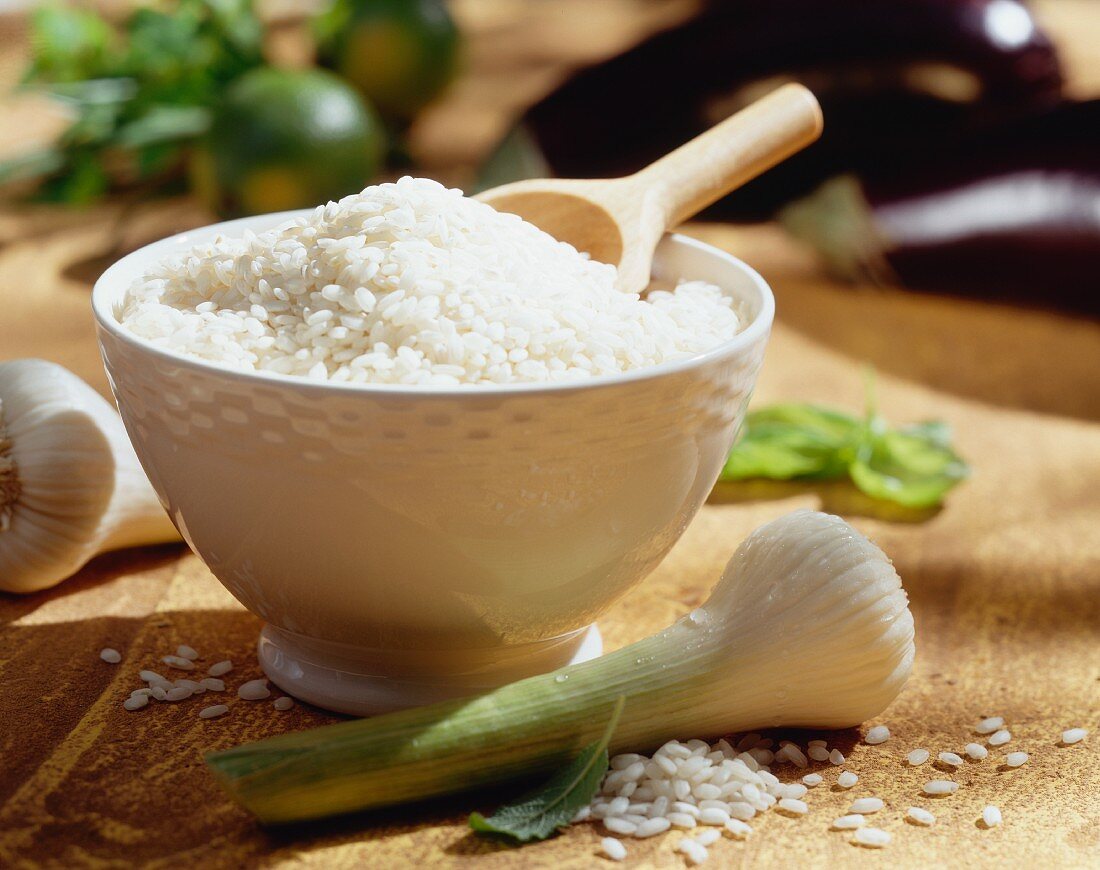 Dish with rice and wooden scoop, in front garlic