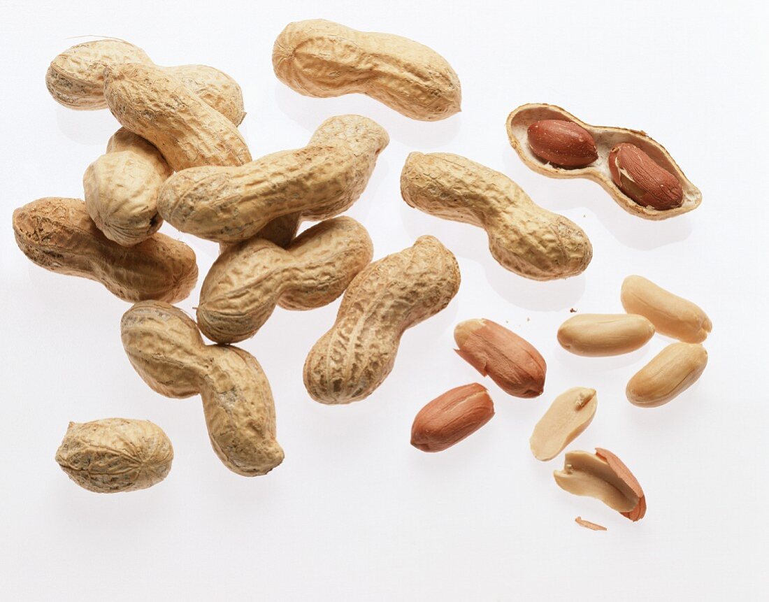 Several opened and unopened peanuts in heap