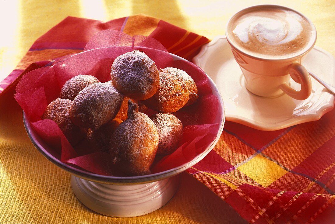 Fritters in bowl, cup of cappuccino behind