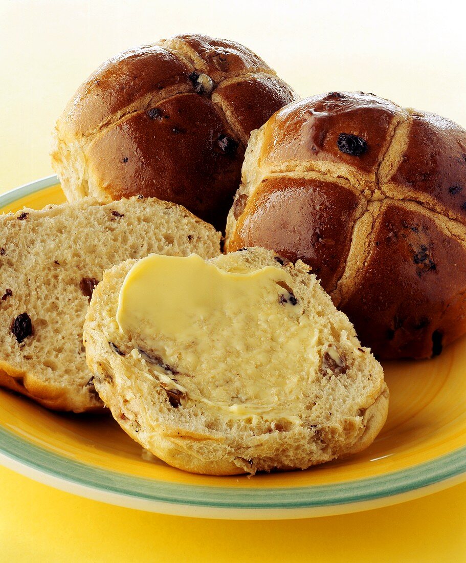 Buttered hot cross buns on plate