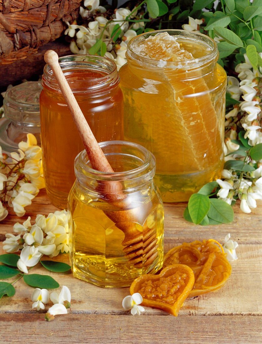 Drei Gläser Honig mit Honiglöffel und Honigwabe