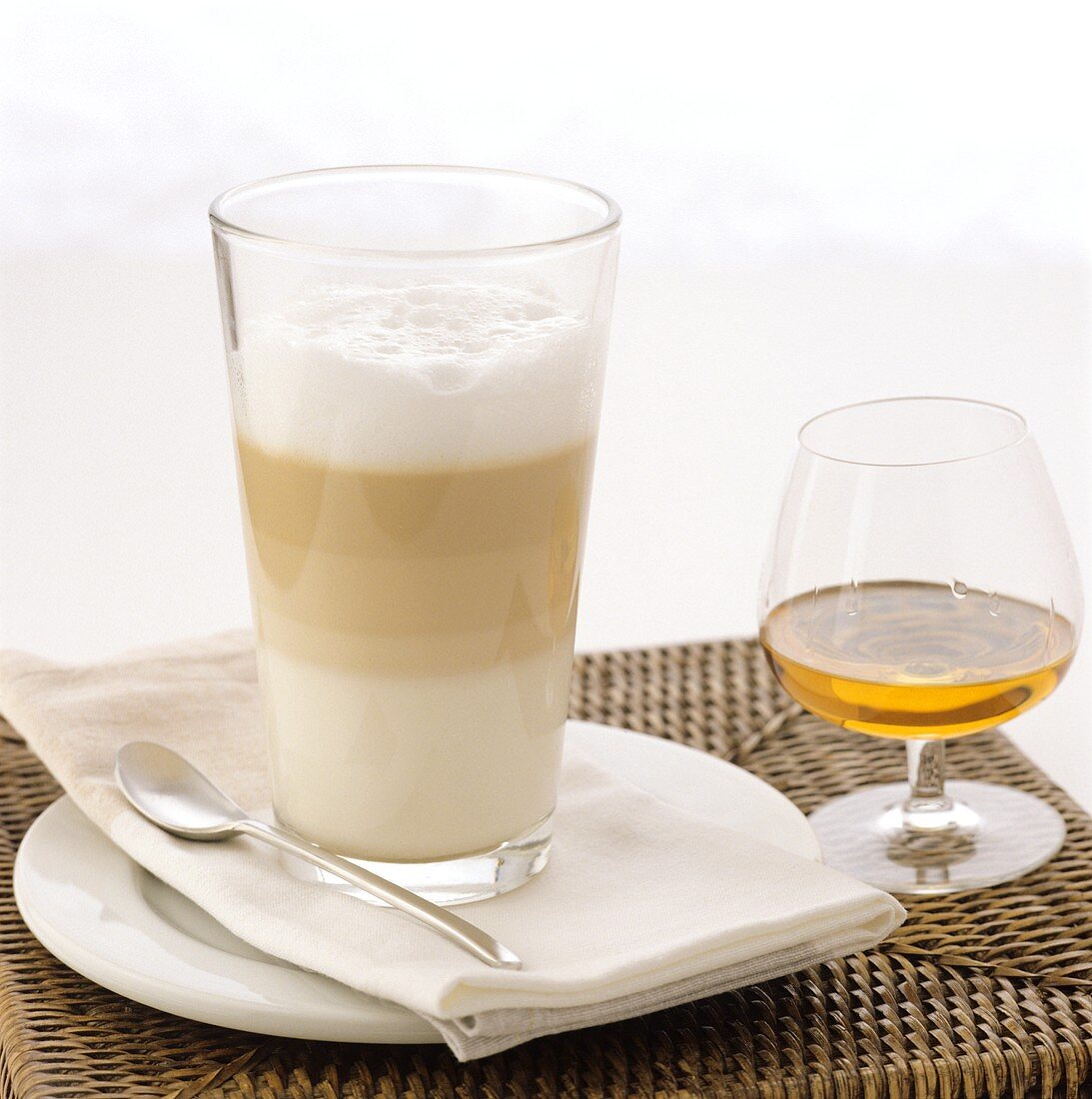 A glass of latte macchiato and a glass of cognac