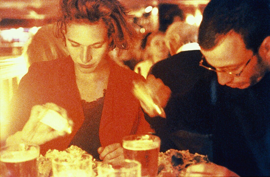 Man and Woman in Restaurant; Salting Food