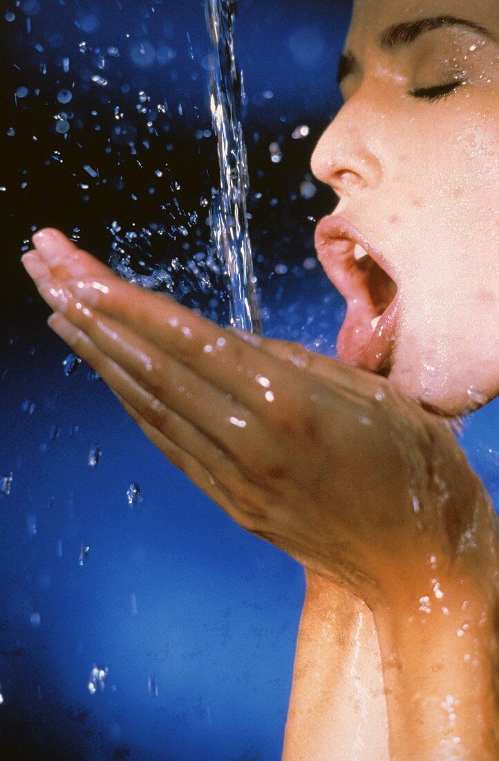 Junge Frau trinkt Wasser aus ihren Händen