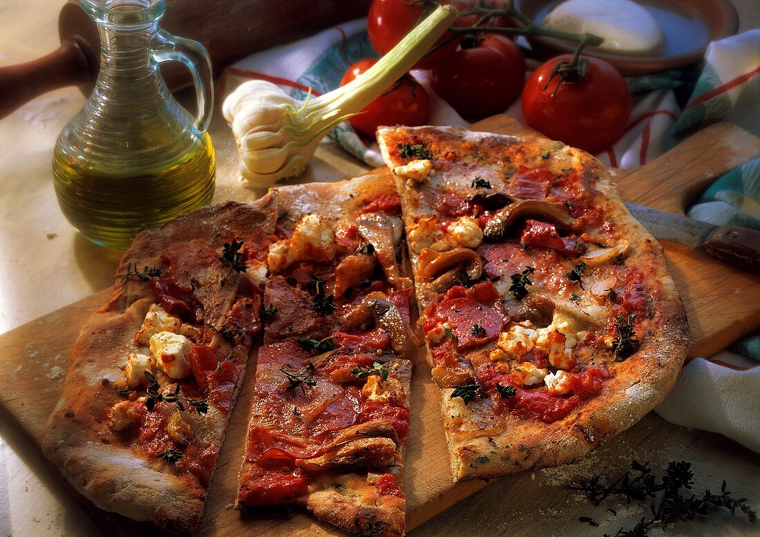 Pizza aus Kräuterteig mit Salami, Mozzarella & Pilzen belegt