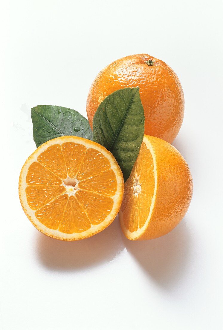 Oranges, one whole and two half fruits and leaves