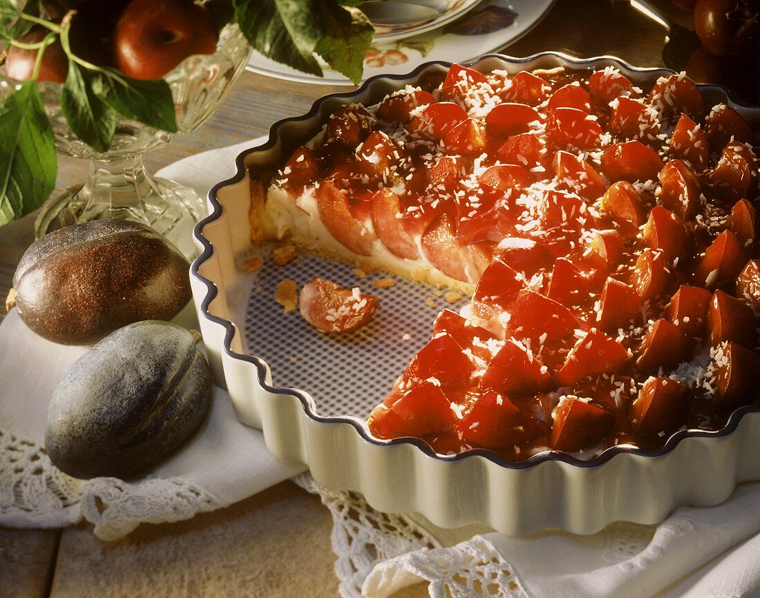 Plum and coconut tart in a china dish, decoration: plums