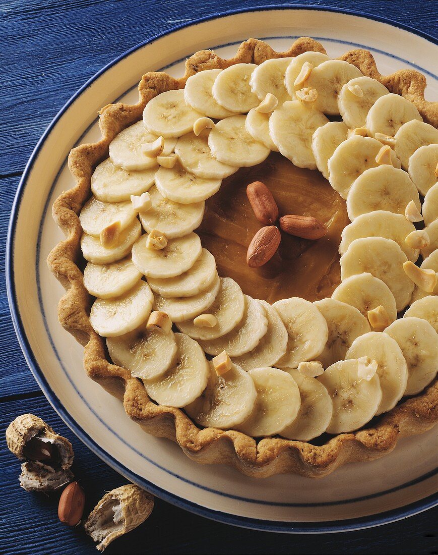 Short pastry banana tart with peanuts on plate