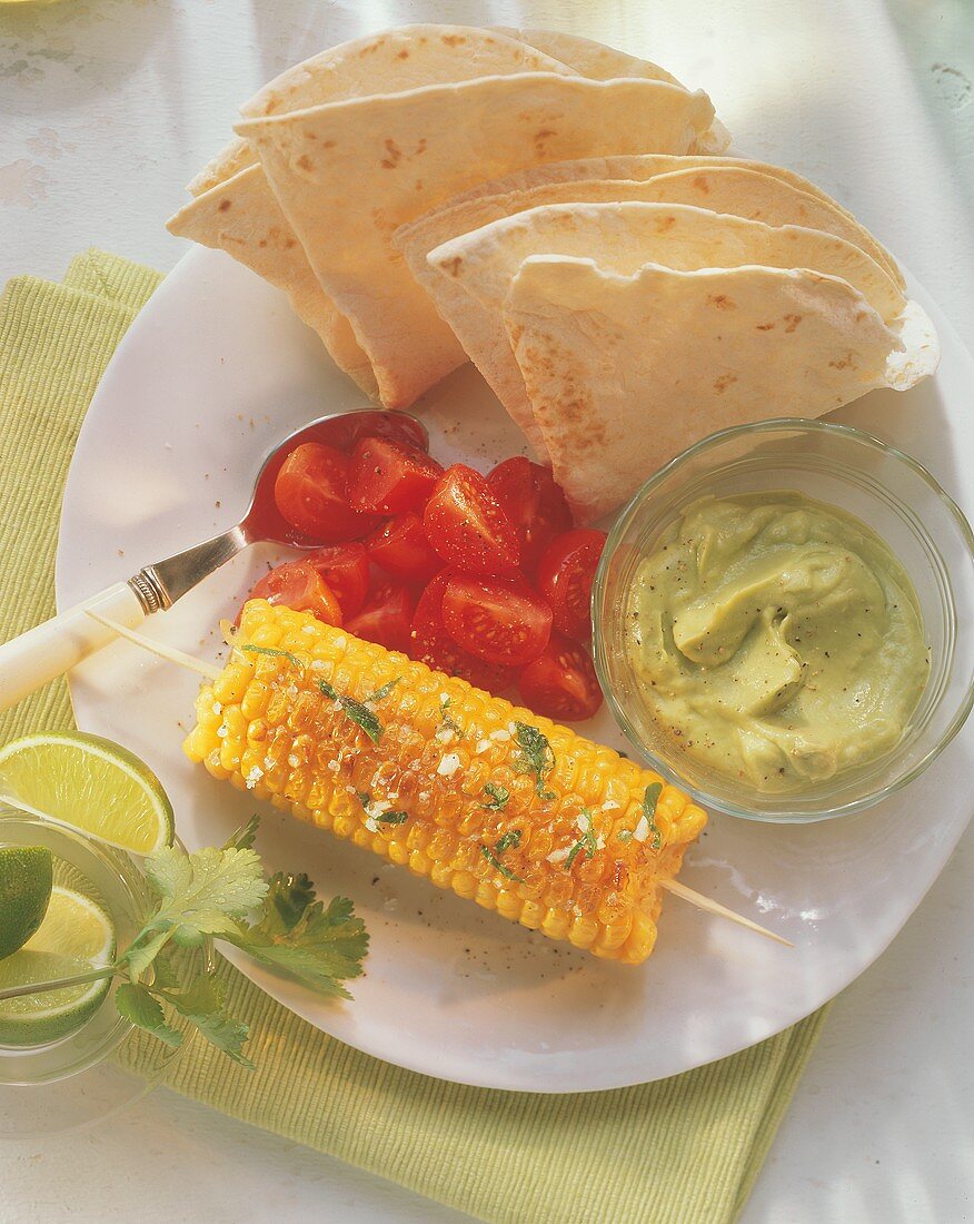 Grilled corncobs with avocado dip and tortillas