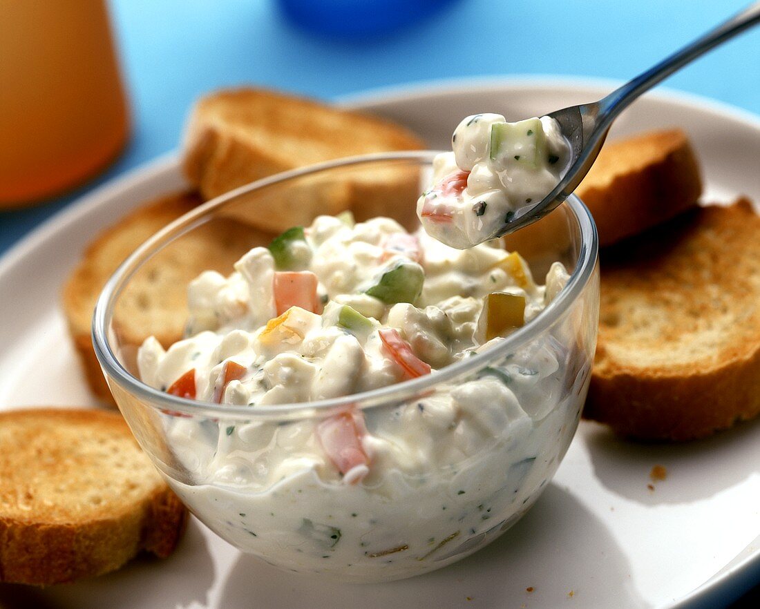 Gemüsesalat mit Mayonnaise, dazu geröstete Brotscheiben