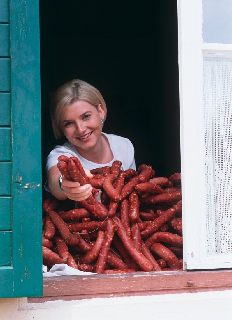 Young woman with sausages at window