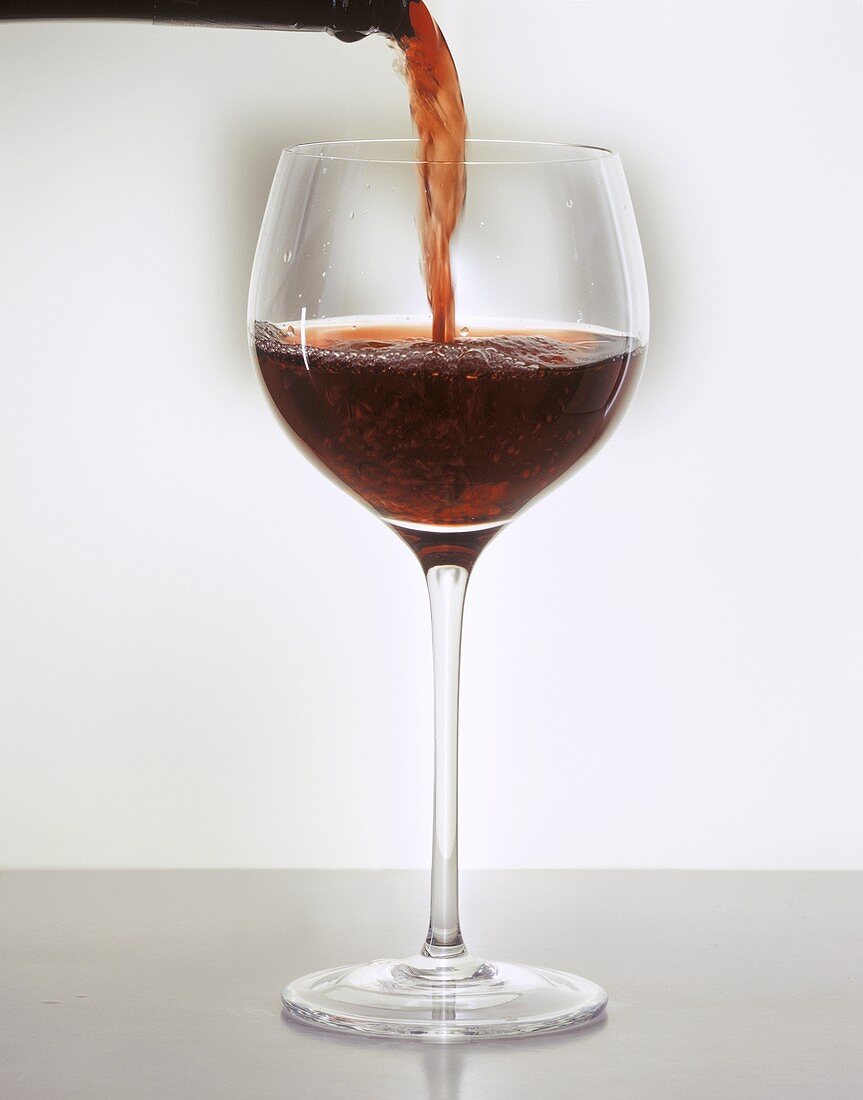 Ein Glas Rotwein einschenken