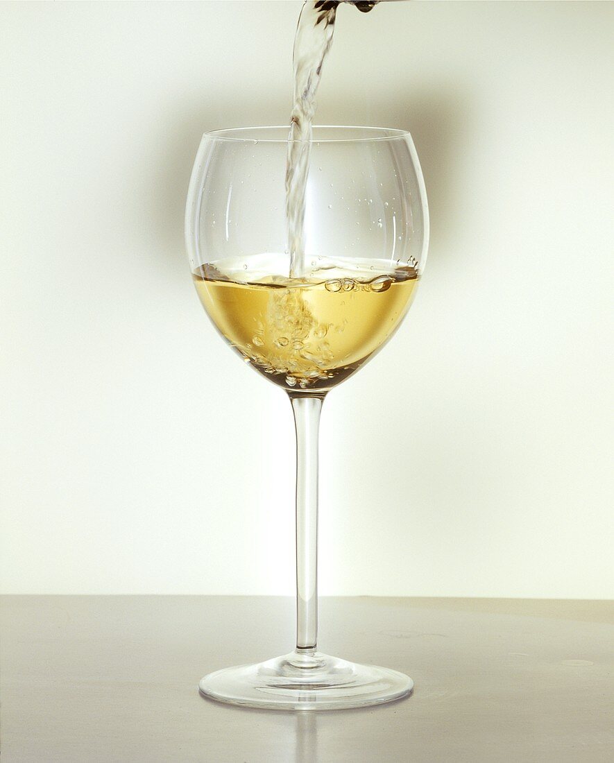 Ein Glas Weißwein einschenken