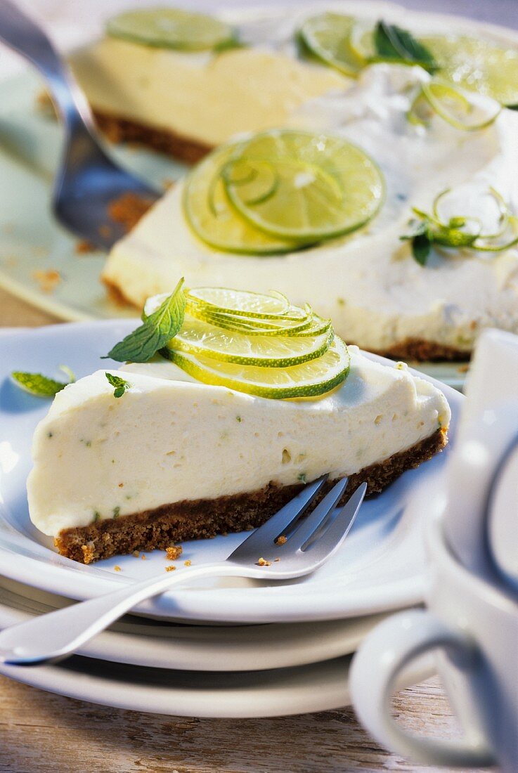 A piece of lime pie in front of pie with piece cut