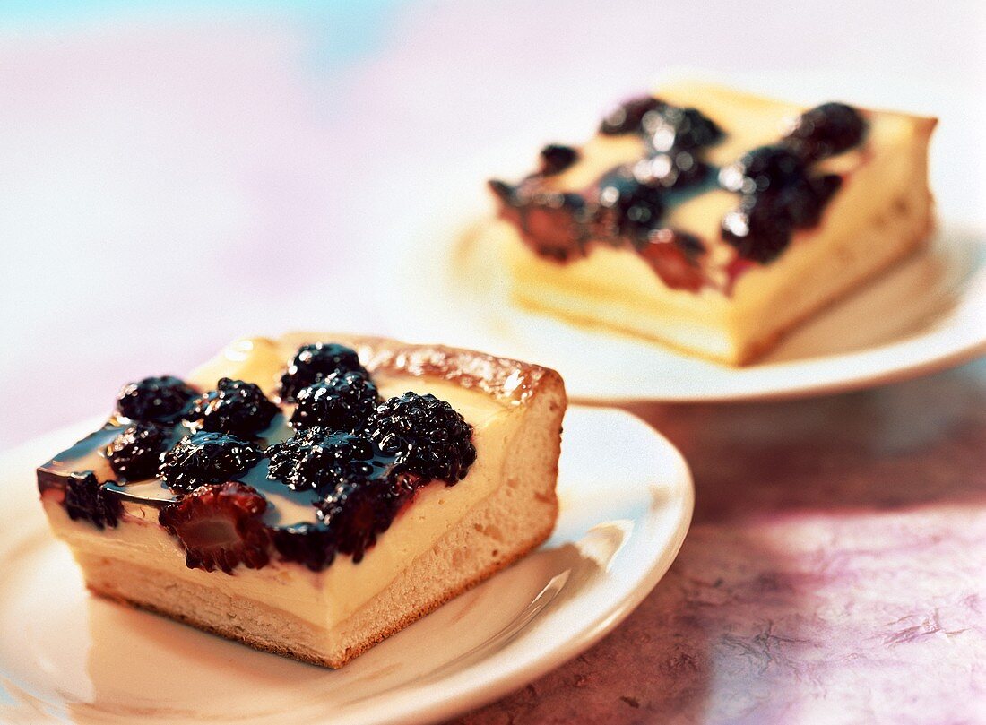Two pieces of sour cream cake with blackberries