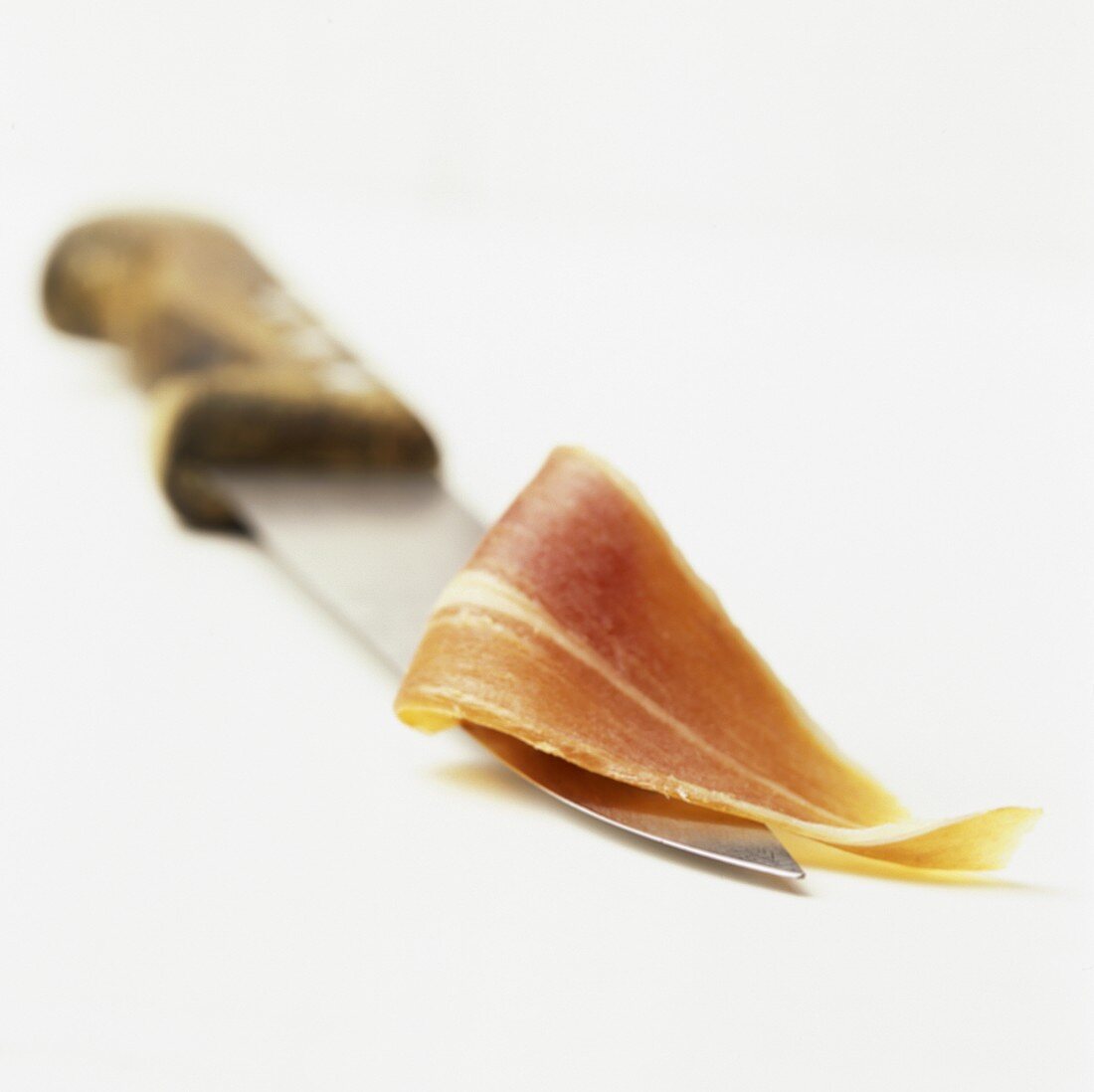 Eine Scheibe Serrano-Schinken auf Messer mit Holzgriff
