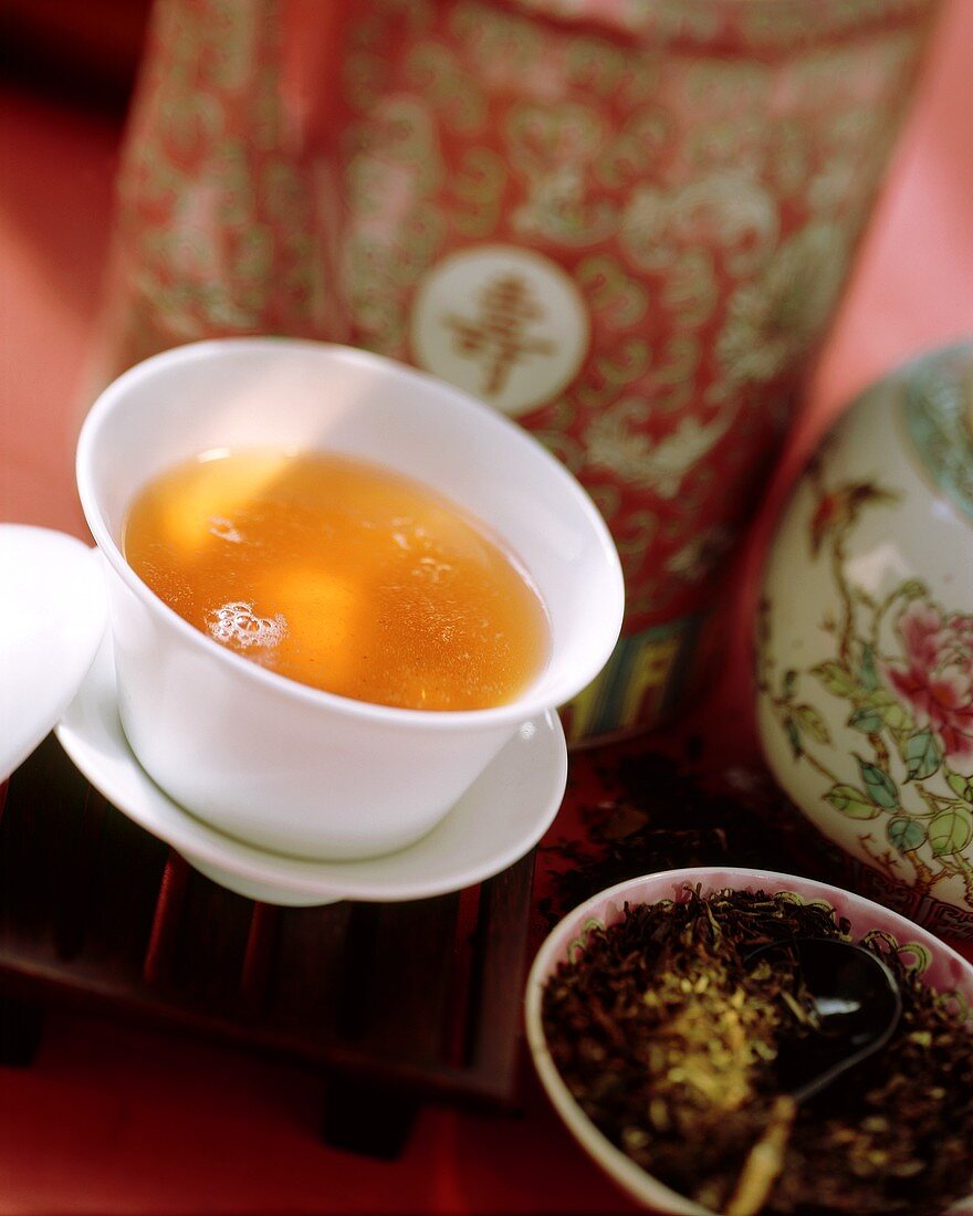 Schwarzer Tee in Trinkschale, daneben Teeblätter im Schälchen