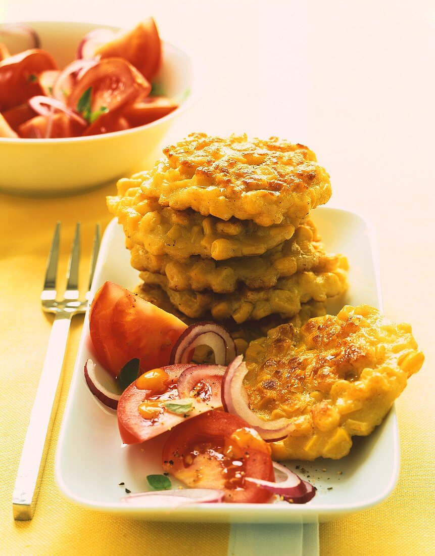 Corn pancakes in a pile, with tomato salad