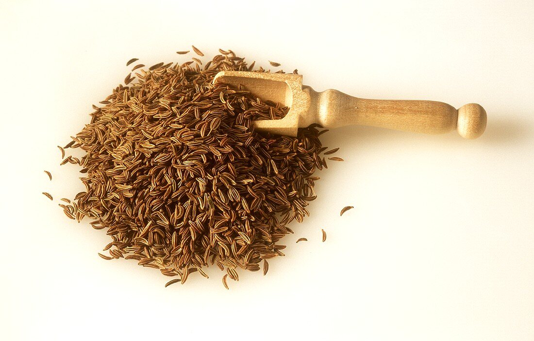 A heap of caraway with small wooden scoop