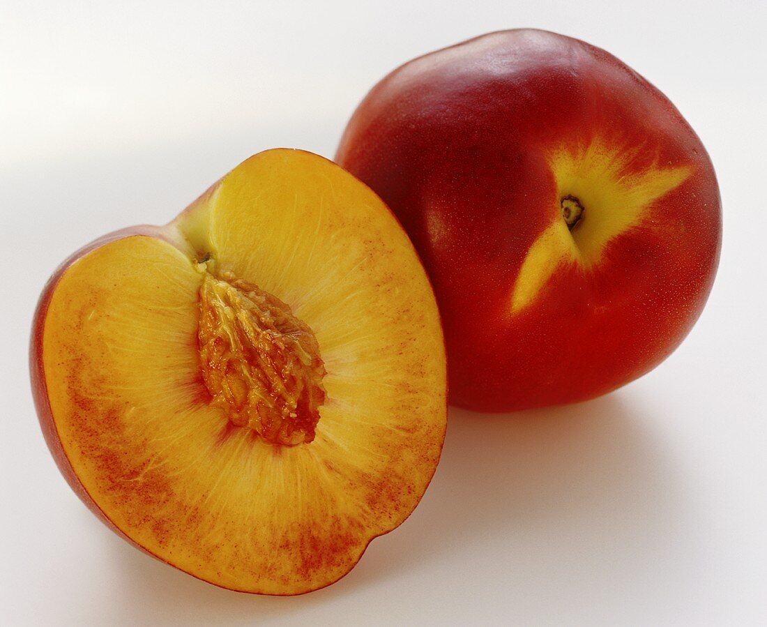 Half a nectarine with stone and a whole nectarine