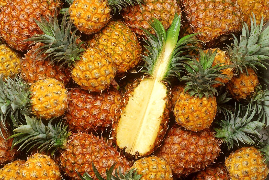 Many pineapples, one cut into (filling the picture)