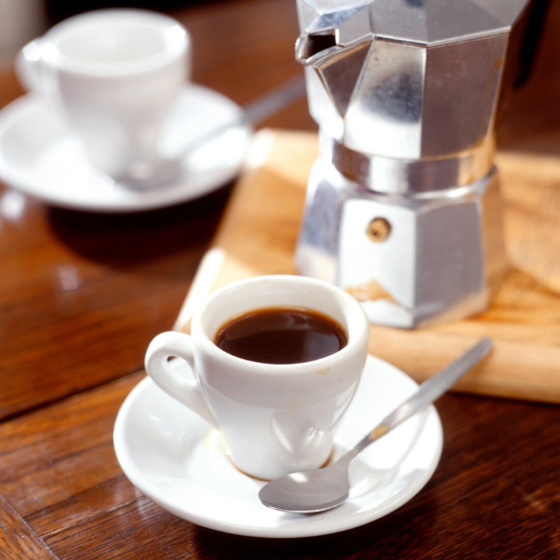 A cup of espresso in front of Italian espresso pot